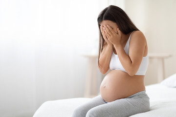 Young pregnant woman feeling sad and crying at home