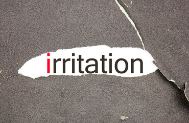 irritation symbol. The word annoyance with a red letter on the background of sandpaper, rough, hard paper. Black background, copy space. Irritability, psychological problem, concept.