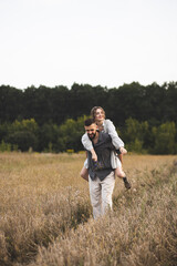 Naklejka na ściany i meble Loving couple of man and woman in the field. A couple in love is walking in the field and enjoying life. Romance and love. Happy and romantic couple. Love between two people.