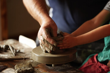Pottery workshop. A potter teaches a child to make a clay pot. Great hobby and education activity for students.