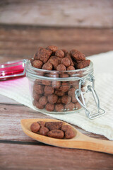 sweet chocolate children's breakfast, balls and pads in a glass jar on a wooden background