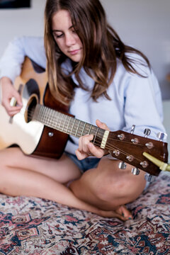 Teen Girl Playing Guitar In Her Bedroom