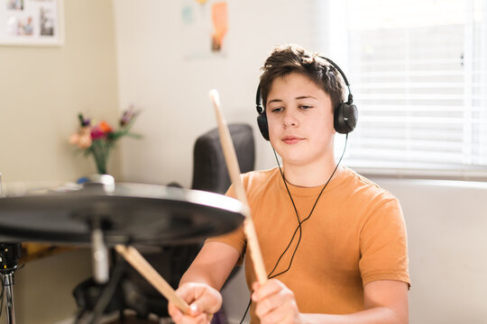 Teen Boy Practising Drums At Home