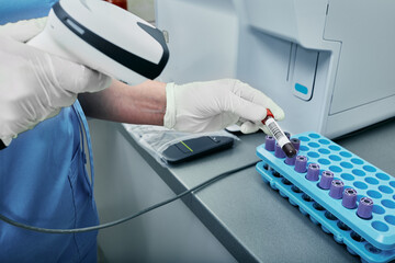 Laboratory technician scanning barcode of test tube with blood. Barcode label on test tube for tracking blood samples