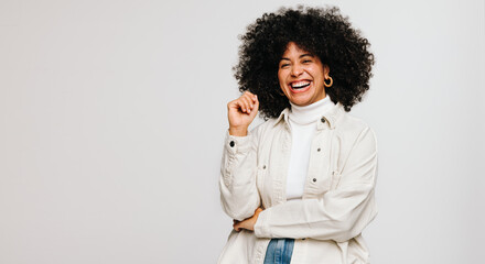 Attractive woman with Afro hair laughing happily while standing in a studio