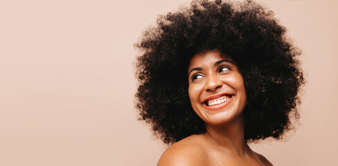 Cheerful woman with Afro hair smiling in a studio
