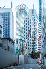 Naklejka premium Tower cranes in construction site among skyscrapers