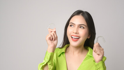 Young smiling woman holding invisalign braces in studio, dental healthcare and Orthodontic concept.