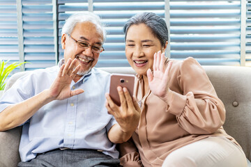 Happy elderly retired couple making video call with mobile phone, gesturing hi, having pleasant conversation,chatting with grown up children grandchildren using wireless internet connection at home - obrazy, fototapety, plakaty