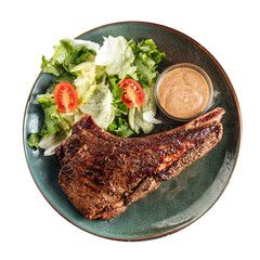 Portion of grilled beef steak with salad and sauce