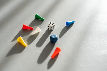 Colorful game chips and two dice are laid out on a gray background: entertainment, games at home for the whole family, the concept of Board games. Board game. Table games, space for text