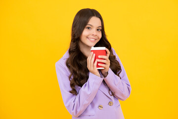 Teenager girl holding a hot cup of coffee or tea. Child with takeaway cup on yellow background, morning energy drink beverage. Happy face, positive and smiling emotions of teenager girl.