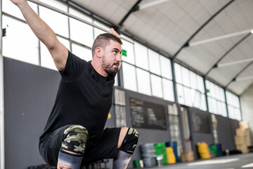young adult man indoors gym training exercising weight lifting squatting