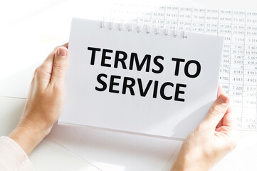 Terms of Service text on a notepad in the hands of a girl at the table