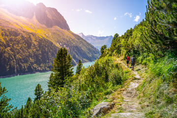 Alpine track and two hikers at mountain lake