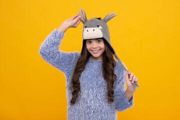 Modern teenage girl 12, 13, 14 year old wearing sweater and knitted hat on isolated yellow background. Happy face, positive and smiling emotions of teenager girl.