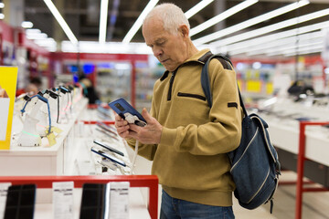 senor man pensioner buying modern tablet digital in showroom of digital electronic goods store