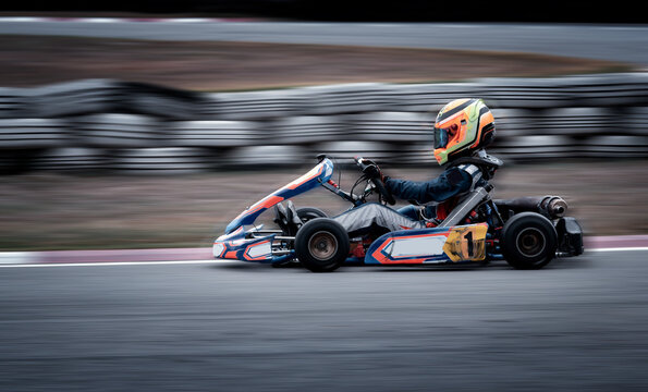 Go kart racing field, racer wearing safety uniform on competition tournament.	