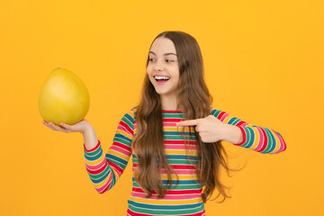 Funny teenage girl hold citrus fruit pummelo or pomelo, big green grapefruit isolated on yellow background.