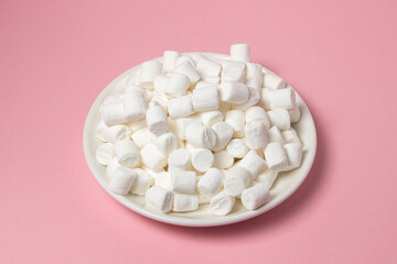 Fototapeta na wymiar Mini marshmallows on a pink background. A plate full of marshmallows. Dessert ingredient