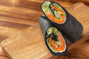 Black tortilla wrap with salted salmon and vegetables