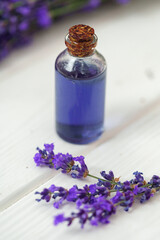 Obraz na płótnie Canvas Herbal oil and lavender flowers on white wooden background