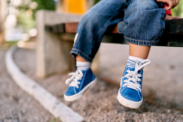 Baby feet in small blue lace-up sneakers. High quality photo