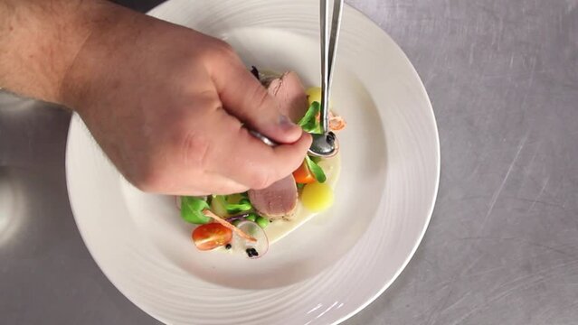 The chef prepares a salad of greens and black caviar