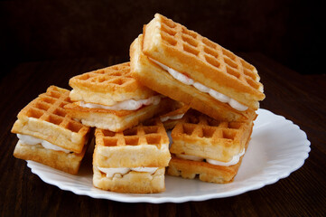 Fresh Viennese waffles with white cream on a white plate.