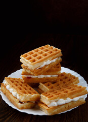 A pile of ruddy Viennese waffles lie on a white plate.