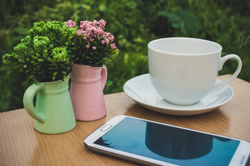 The mobile , a vase of flowers and a cup of coffee