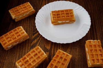 Viennese waffles lie on and next to a white plate.
