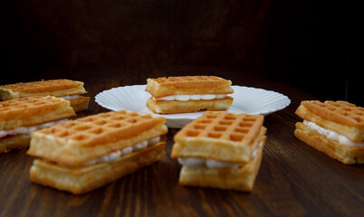 Viennese waffles lie on and next to a white plate.