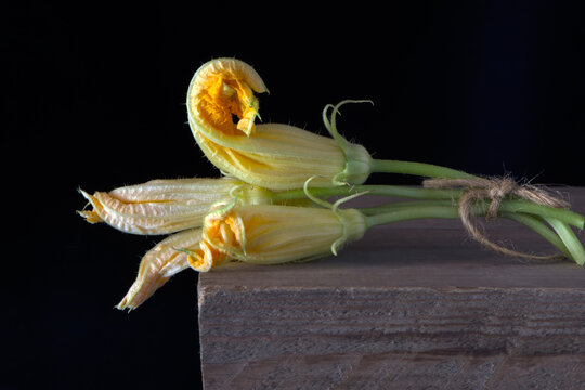 yellow flowers zucchini vegetables on a wooden table