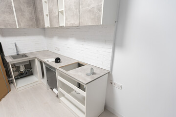 Modern kitchen with empty Built-in dishwasher, Stainless steel undermount kitchen sink. White tone kitchen.