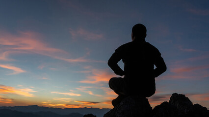man meditating pastel on high mountain in sunset background.