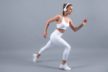 Fototapeta na wymiar Fitness woman runner. Sporty strong cheerful young woman posing on gray isolated background. Caucasian female athlete, muscular, sportive woman. Concept of youth healthy lifestyle.
