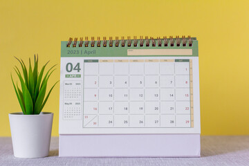 Desktop calendar for April 2023 on a yellow background.