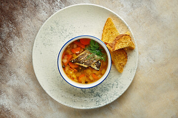 Fish soup with sea bass fillets in a white plate. Close-up, selective focus