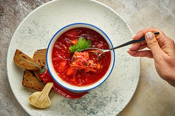 Ukrainian borscht with pickles and rye bread in a white plate. Close-up, selective focus