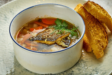 Fish soup with sea bass fillets in a white plate. Close-up, selective focus