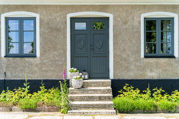 Closed green wooden entrance door with stone stairs and concrete walls of the scandinavian style house