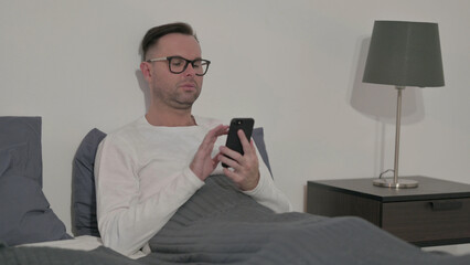 Casual Man using Smartphone in Bed