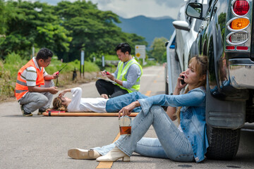 Drunk driver Asian woman holding alcohol bottle sitting and talking on phone, rescue teams helping...