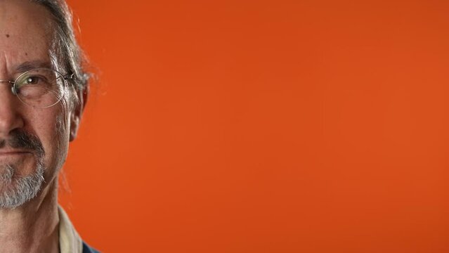 Portrait of photogenic smiling half of mans face isolated on solid orange background.