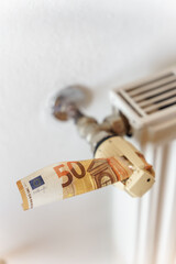 Ein 50 Euro Schein in einem Thermostat am Heizkörper. Heizkosten, sparen.