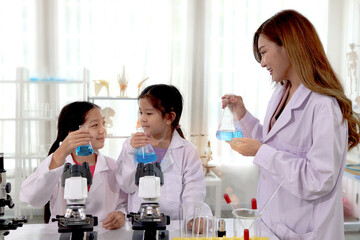 Students and teacher in lab coat have fun together while learn science experiment in laboratory....