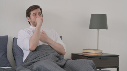 Young Man Coughing while Sleeping in Bed