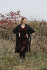 Autumn fashion outdoor portrait of young woman in purple red plush velvet midi dress. 
