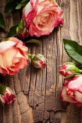 Vintage still life with a few flower of roses on wooden surface